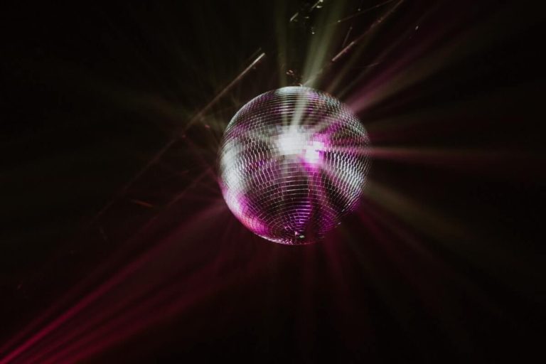 70s Music Quiz Questions and Answers cover photo of a disco ball hanging from a ceiling and sparkling