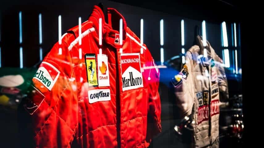 2 Formula 1 racing suits hung up on display in a museum