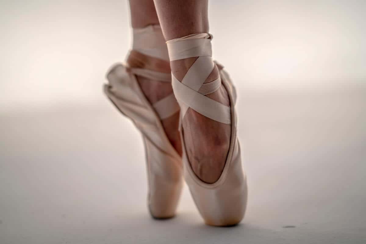 Ballet Quiz Questions and Answers cover photo of a woman's ankles and feet wearing pointe shoes and standing on pointe 