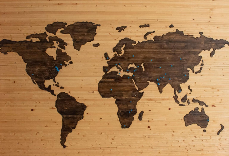 Capital Cities Quiz Questions and Answers cover photo of a wooden world map on the wall, with pins in at different locations