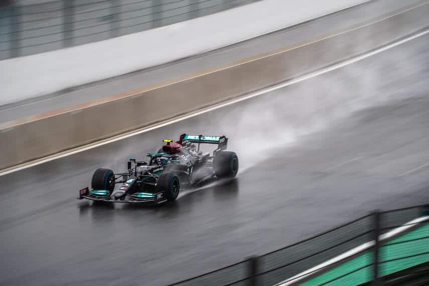 F1 racing car on a wet track with water spraying up behind the wheels