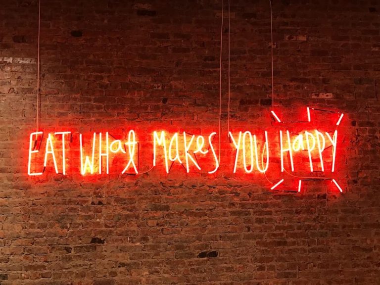 Food Anagrams and Answers cover photo of a neon sign against an exposed brick wall which says: Eat What Makes You Happy