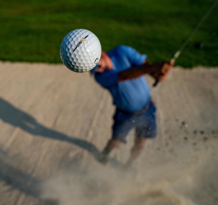 Golfer chipping the ball out of the bunker using a sand wedge