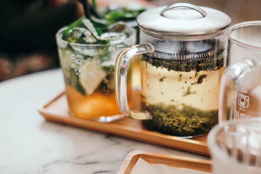 Green tea percolating next to glass of iced tea