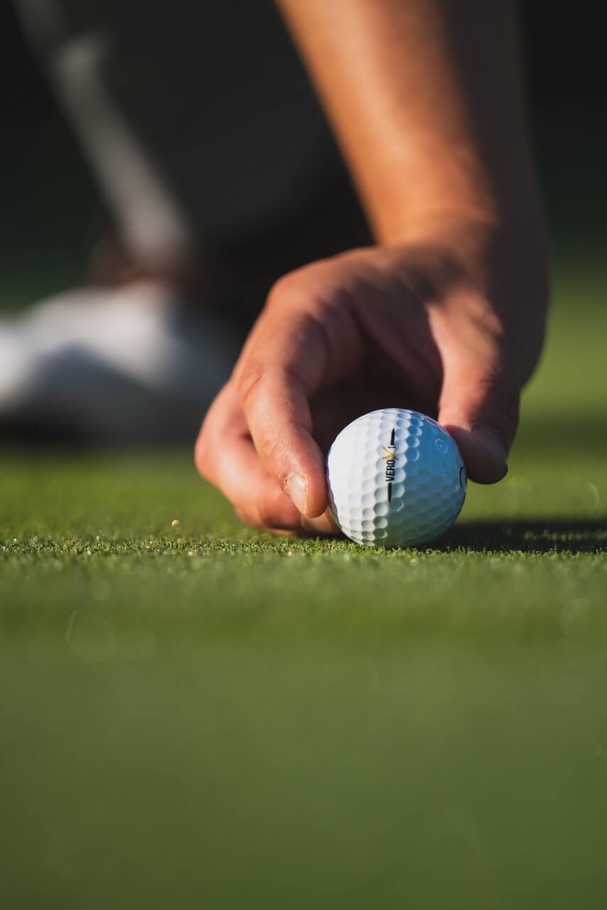 Hand placing a golf ball on the grass