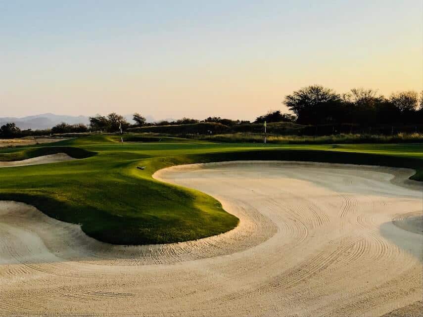 Huge raked sand bunker next to a putting green on a golf course