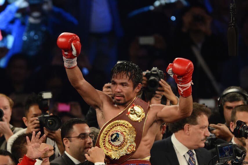 Manny Pacquiao raised about the crowd, arms in the air and belt over his shoulder and chest, celebrating a win