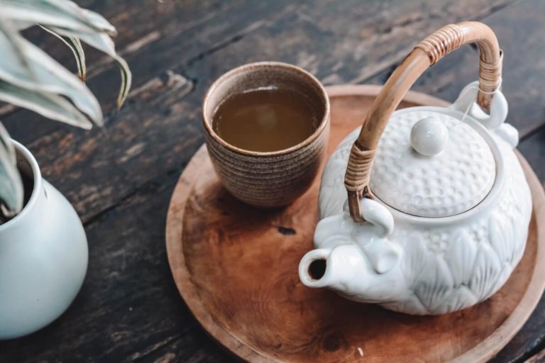 Tea Quiz cover photo of a White teapot next to brown mug of tea on a round wooden tray