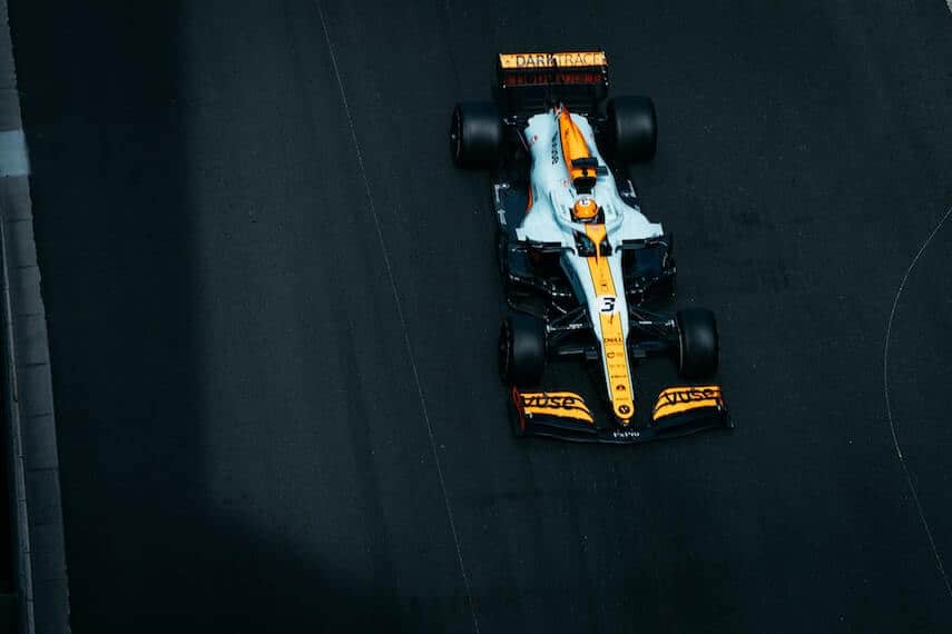 Top down shot of a white, bacl and yellow F1 car on a black tarmac road