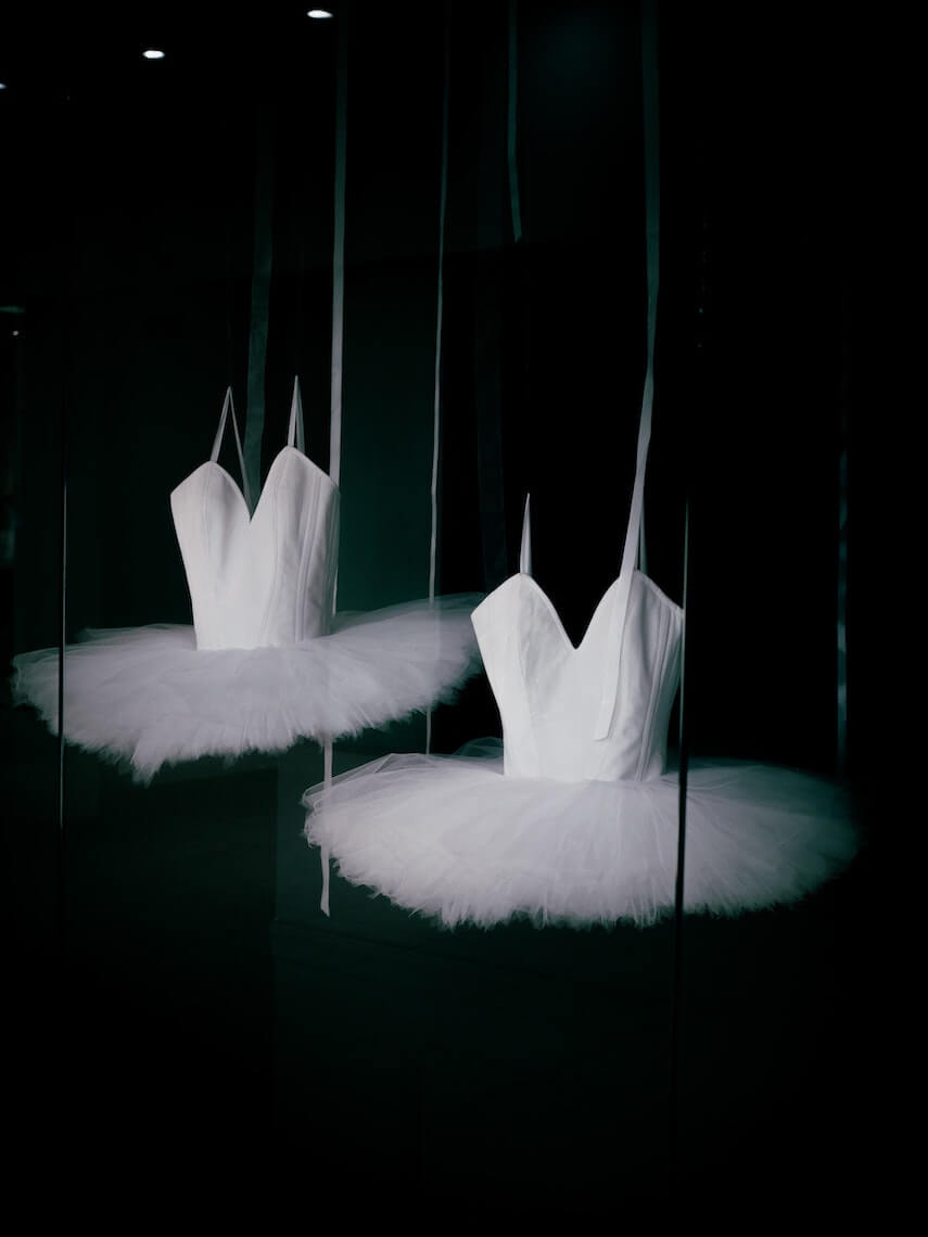 Two white tutus with white bodice hanging on display