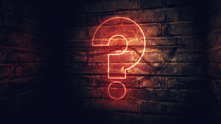 Unusual Quiz Round Ideas cover photo of an illuminated question mark with a red outline on a dark wood effect wall