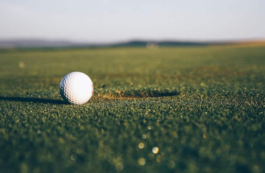 White golf ball next to the hole