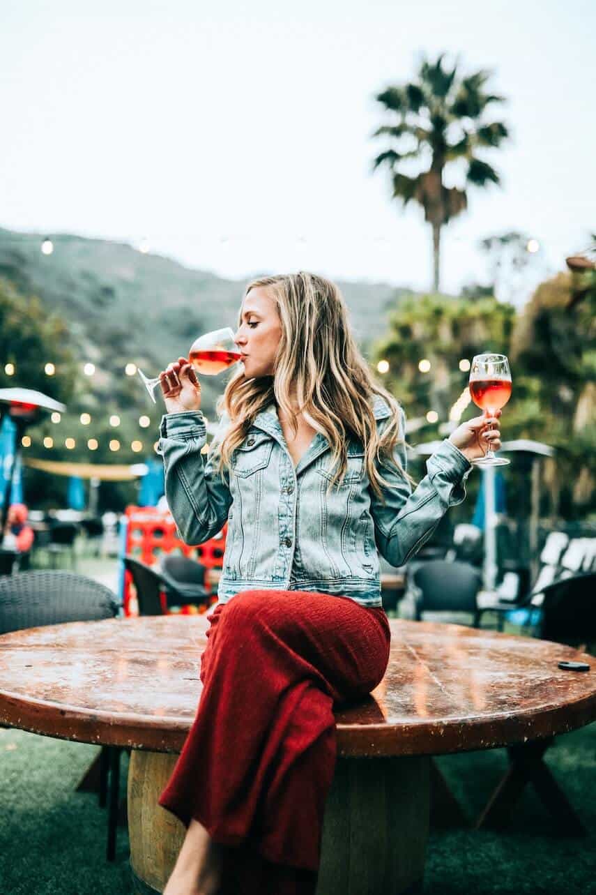 Woman drinking wine with a glass in each hand