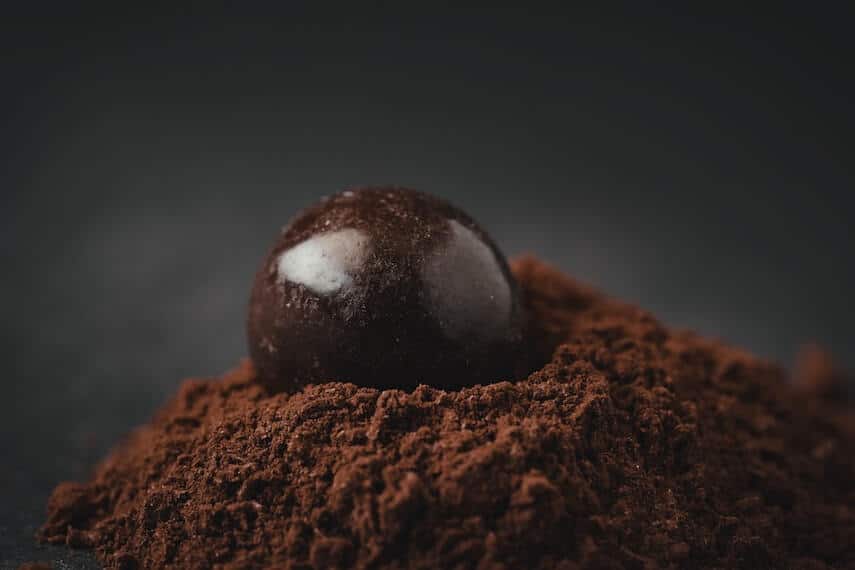 Dark chocolate ball on a mound of powdered chocolate
