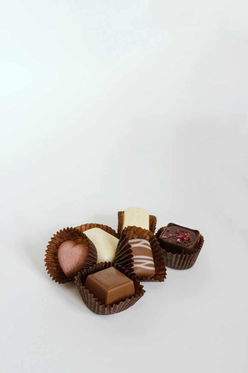 Individual chocolates in brown paper casings in different shapes - a square, a heart and an oblong