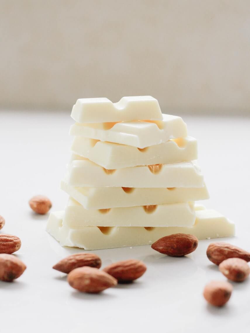 Stack of white chocolate square blocks, with almonds scattered around the base