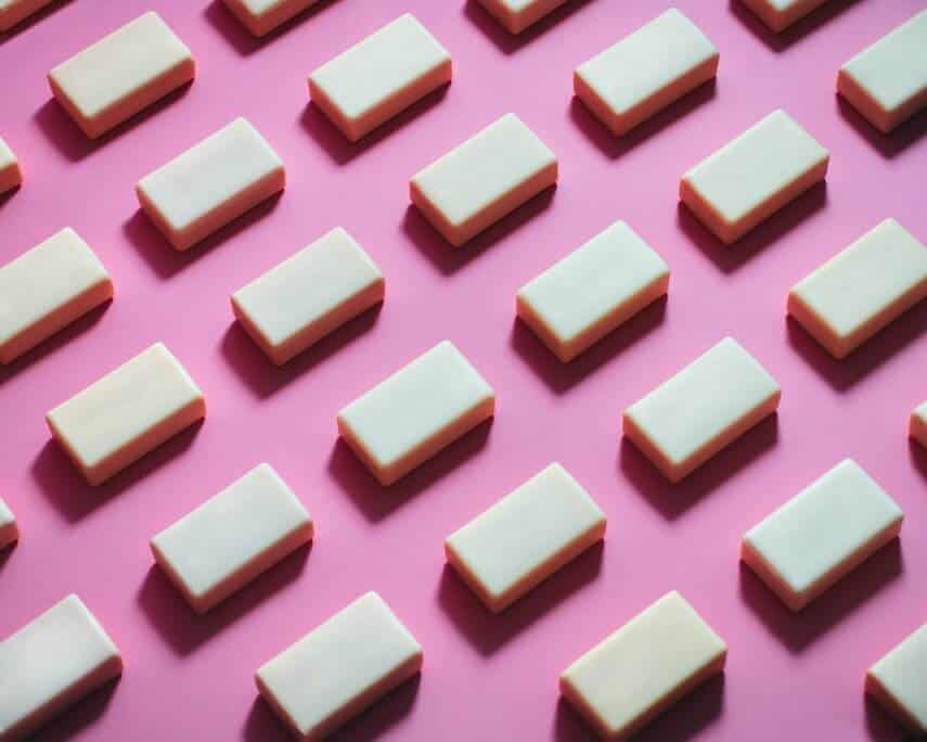 White chocolate blocks, laid out in diagonal lines on a pink surface