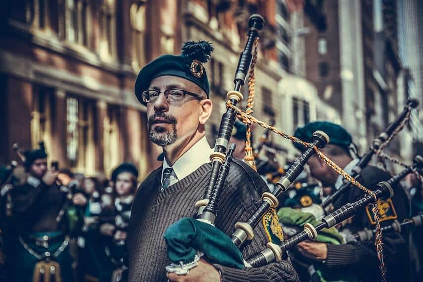 Bearded an wearing glasses and green beret holding green bagpipes
