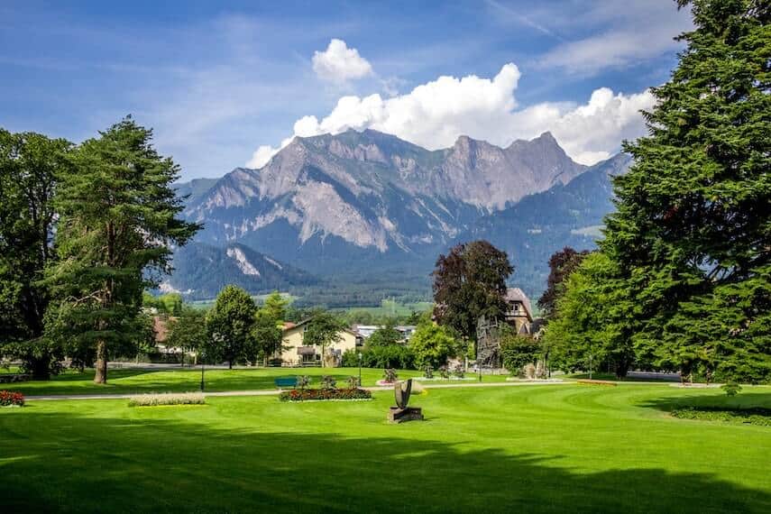 Manicured gardens, lush green grass with mountain in the background in Switzerland