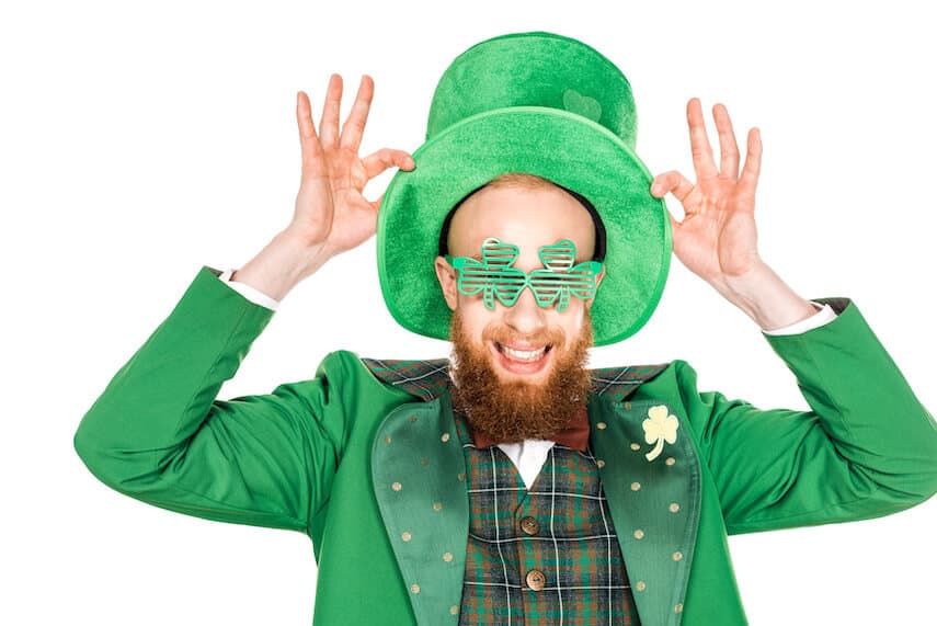 Smiling Bearded man wearing a green suit and wearing shamrock glasses