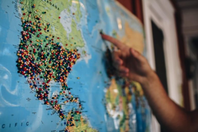 US Geography Quiz Questions and Answers cover photo of a large map on the wall covered in multicolored push pins dotted across America