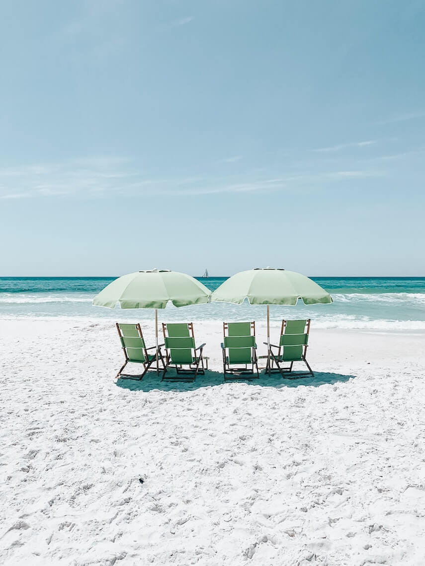 4 green deckchairs an two umbrellas on the beach