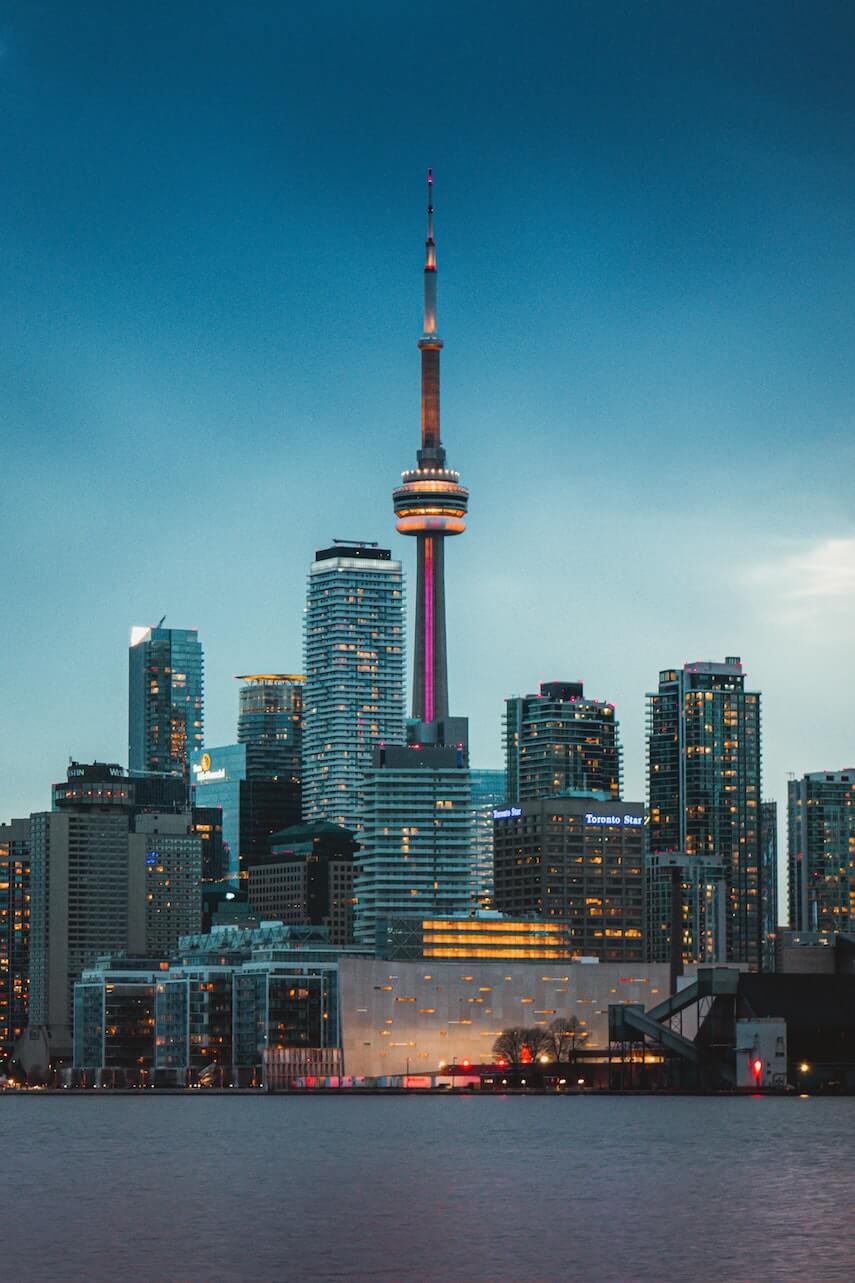 CN Tower surrounded by skyscrapers lit up at night