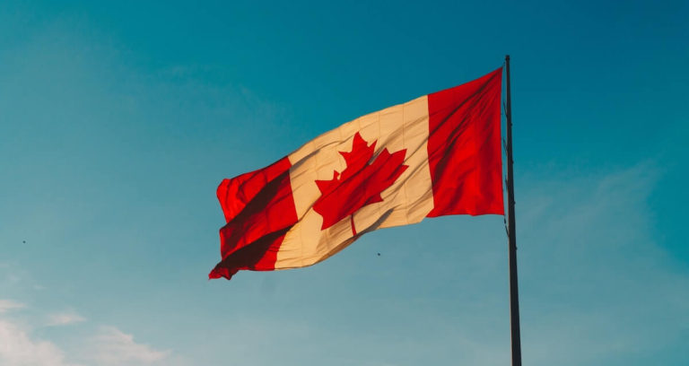 Canada Trivia Questions and Answers cover photo of a Canadian Flag flying under a deep blue sky