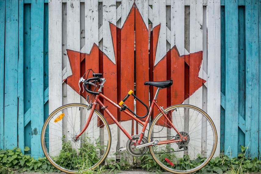 Canadian maple leaf pained on a fence behind a red pushbike
