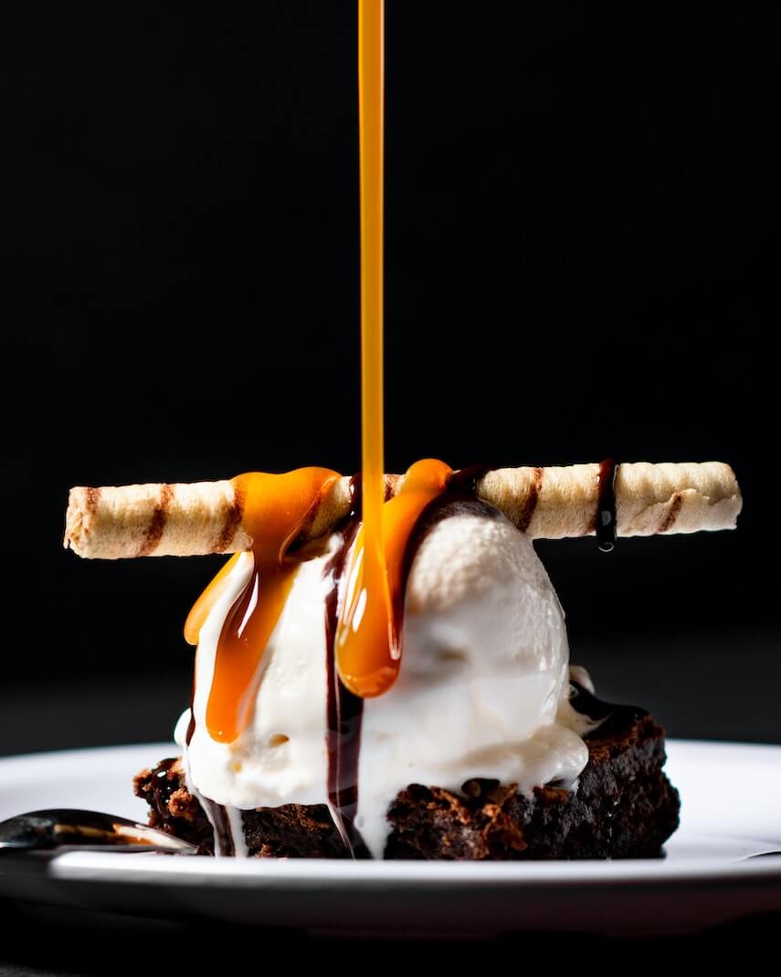 Chocolate Cake Square with a ball of vanilla ice-cream and caramel sauce being poured on top