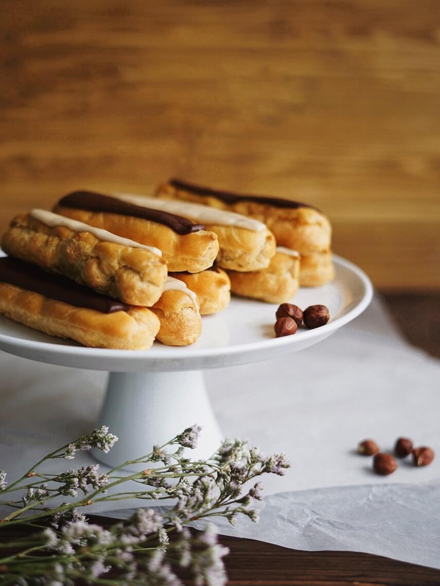 Chocolate covered eclairs on a white circular cake stand