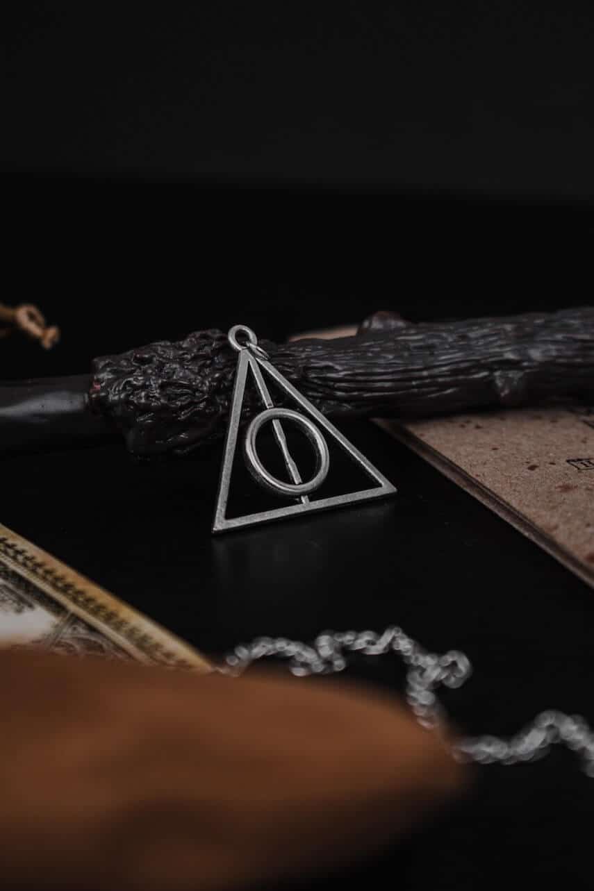 Deathly Hallows Symbol in metal leaning agianst a wooden wand