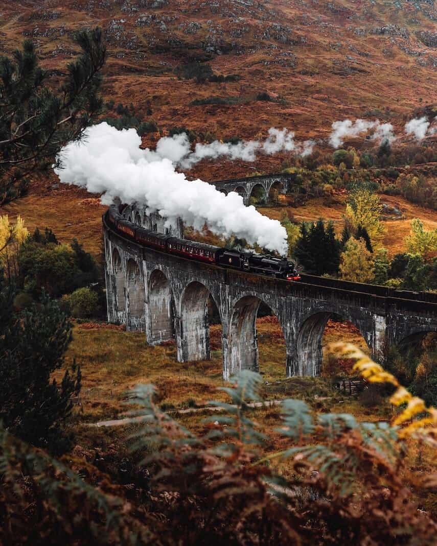 Hogwarts Express steam train crossing the arched viaduct in Scotland