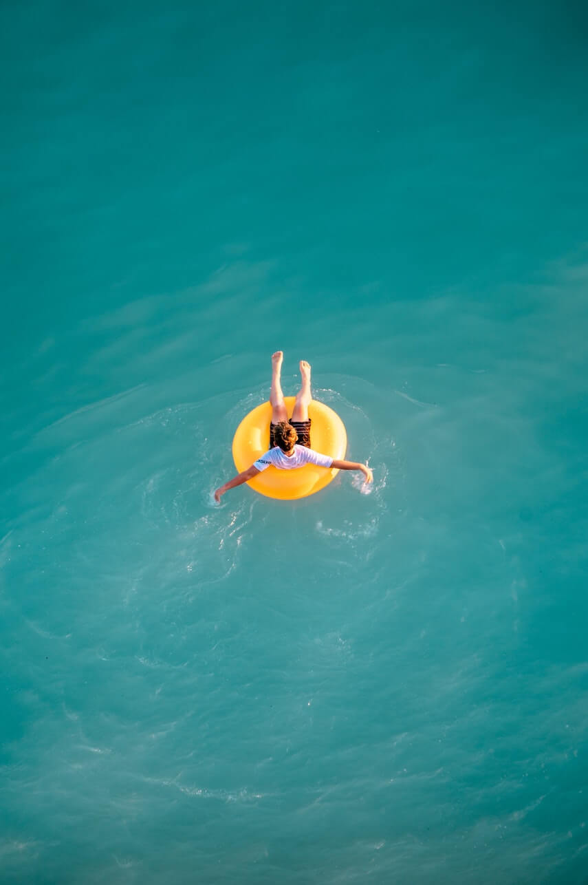 Man in a yellow inflatable ring in the ocean