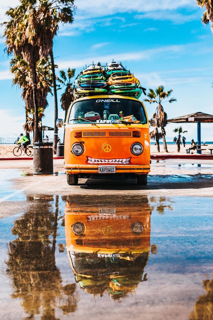 Orange VW campervan with surfboards stacked on the roof