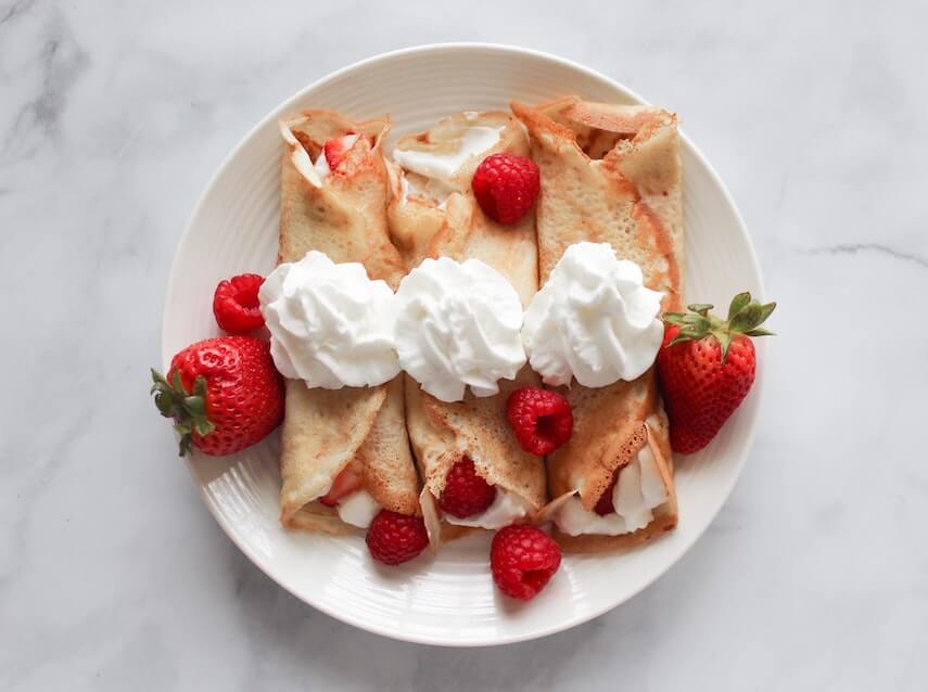 Rolled crepes with strawberries and whipped cream