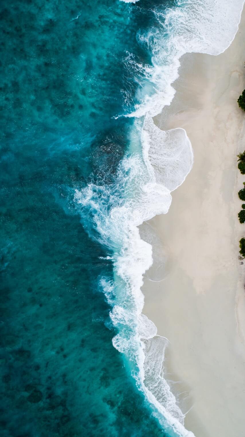 Top down shot of a beach with blue water and white sand