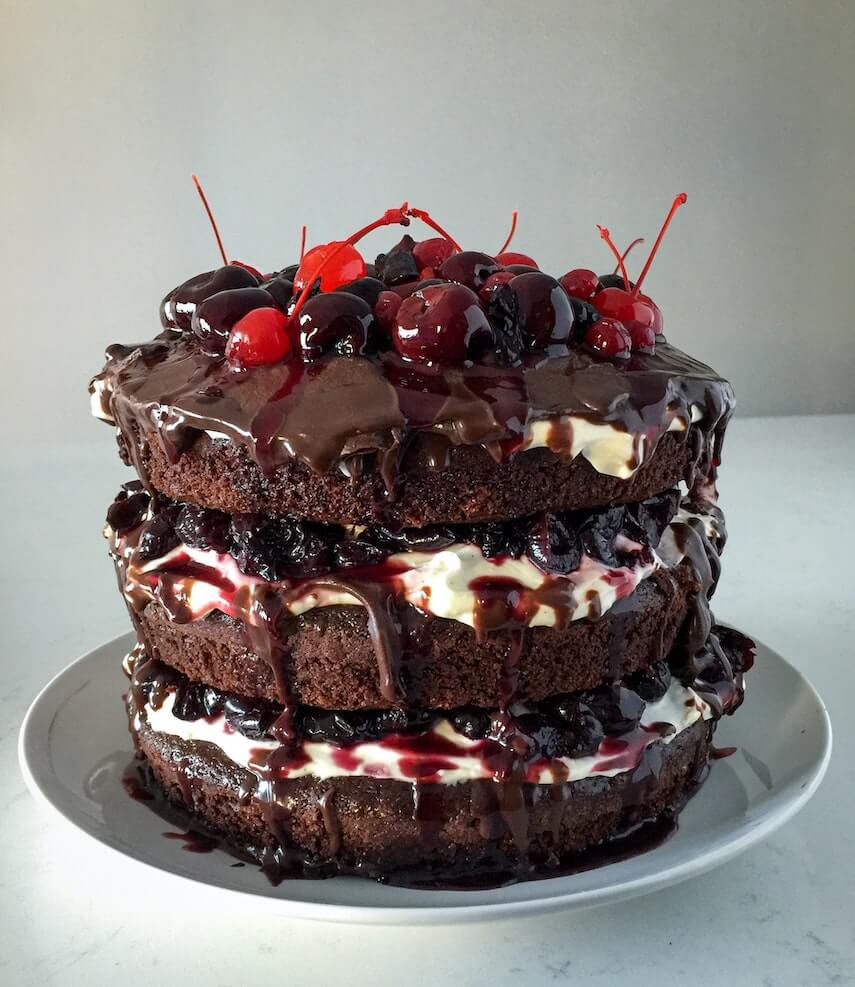 Triple layer chocolate cake filled with cream and cherries topped with goey choclate sauce and black forest fruits