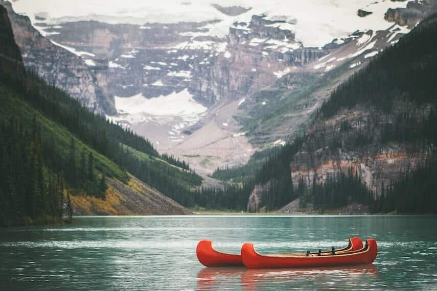 Two Red canoes floating on a mountain lake