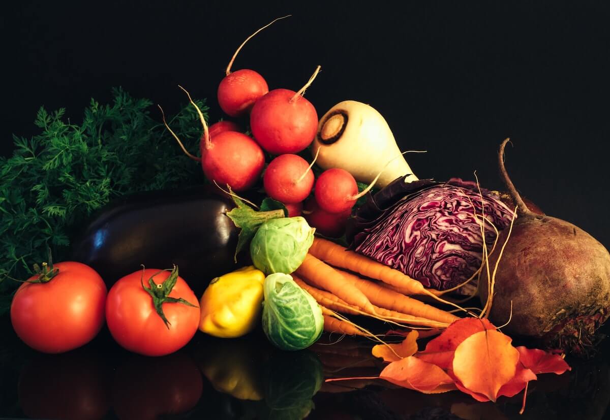 Vegetable Quiz Questions and Answers cover photo of multiple different vegetables laid out against a black background