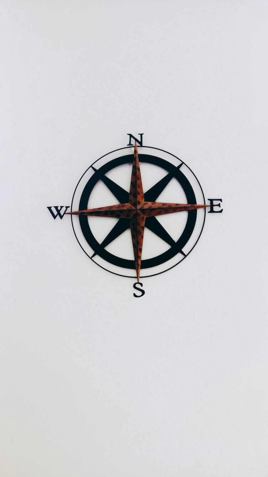 Black compass with 4 star points against white background