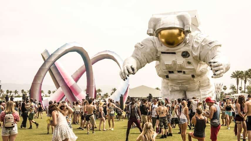 Giant inflatable spaceman and sculpture surrounded by people at Coachella Music Festival