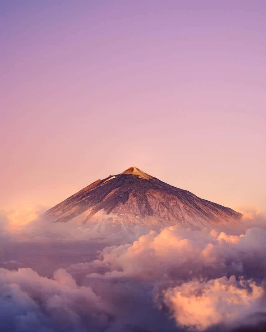 Mount Tiede surrounded by clouds under a light purple sky