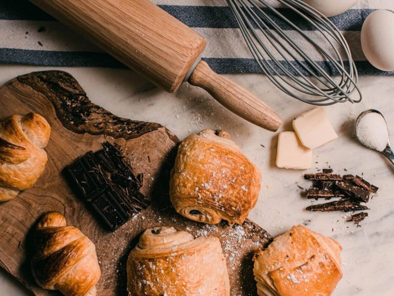 Baking Quiz Questions and Answers cover photo of baked goods on a wooden board next to a wooden rolling pin and metal whisk