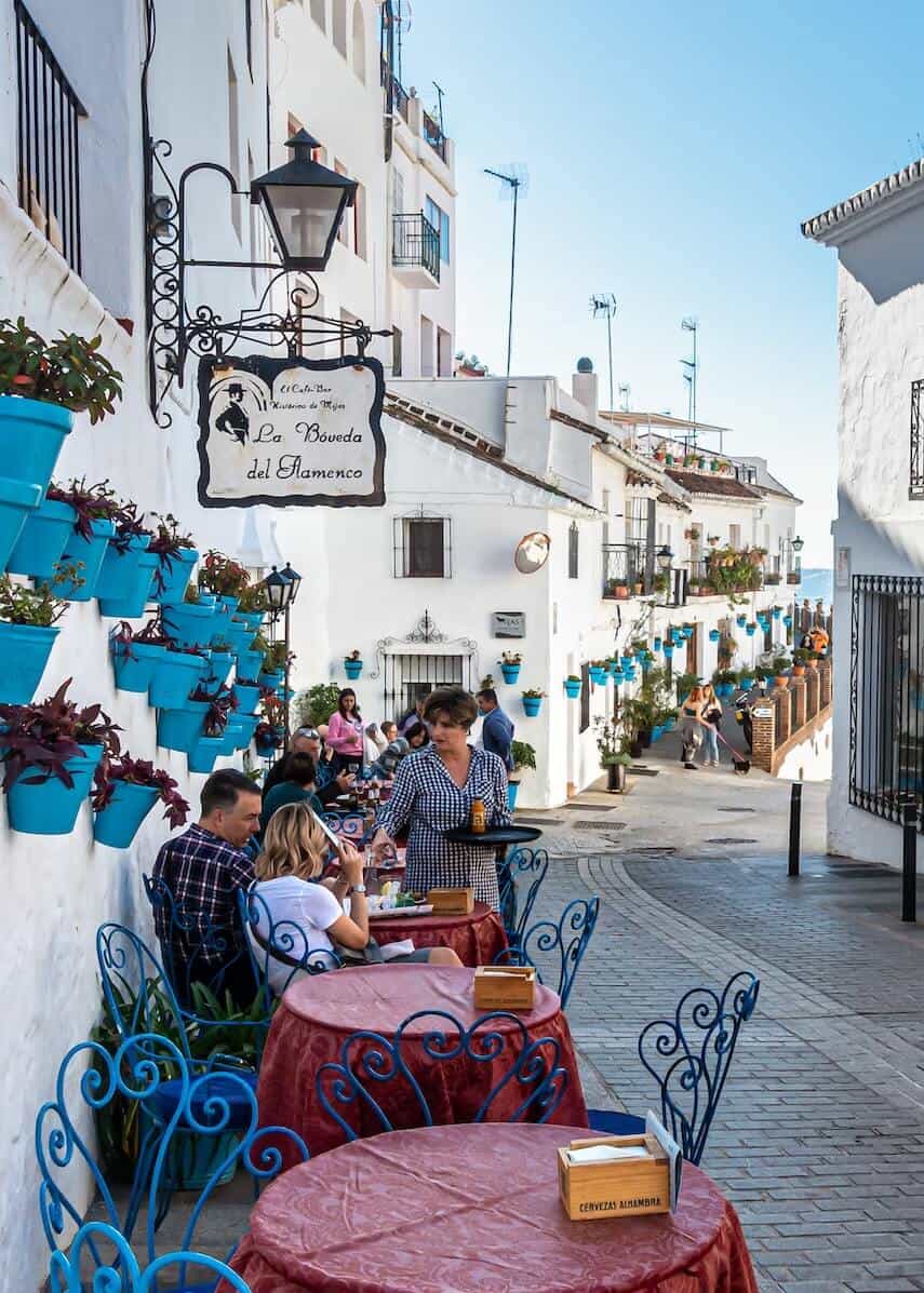 White washed village street in Mijas, blue plant pots hanging of the walls