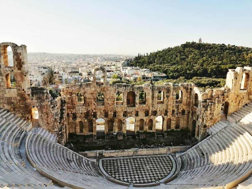Ancient ruins of an open air theater, curved steps leading to the centre where there is a checkered performance area