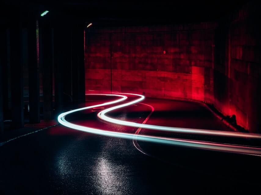 Car light trails coming round a corner in a tunnel