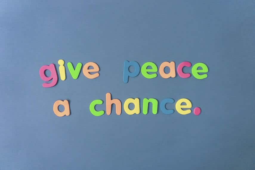 Colourful magnet letters speling out 'Give Peace a Chance' against a blue background