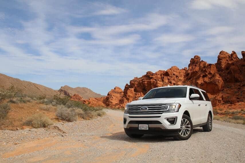 Ford White 4WD SUV on a shale coverd track in front of a red rocky outcrop