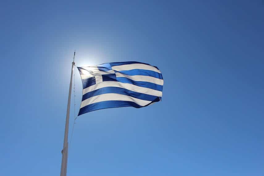 Greek Flag blowing in the wind with the sun directly behind it